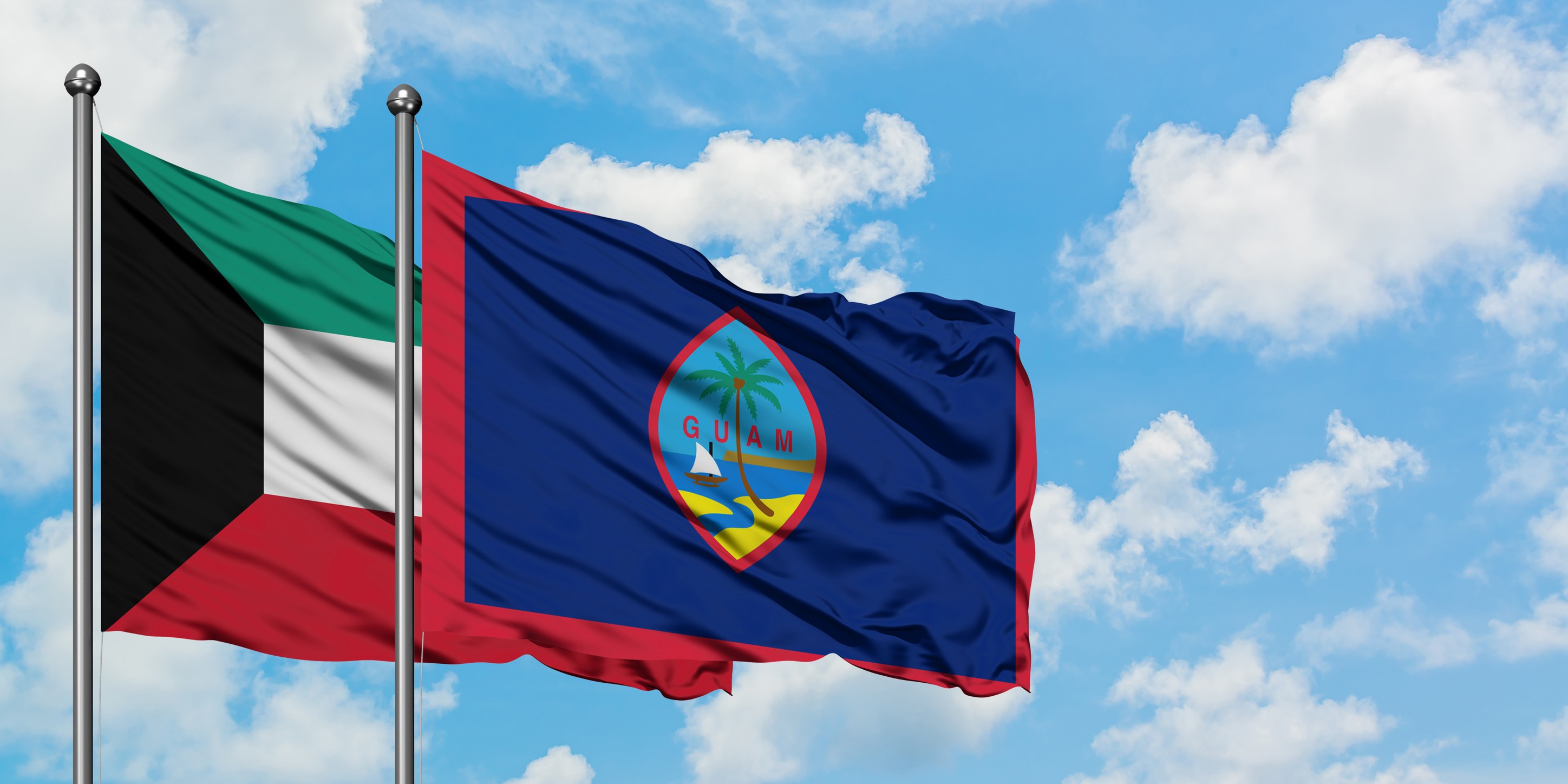 Kuwait And Guam Flag Waving In The Wind Against White Cloudy Blue Sky